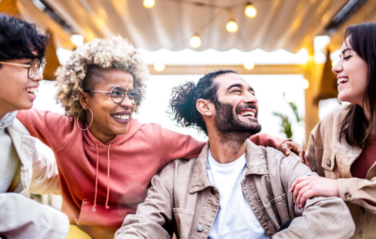 Group of diverse friends from all backgrounds having fun outside under a metal roof.