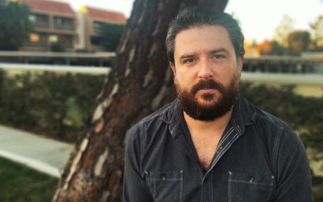 Director David Midell in a black shirt outside looking confident.
