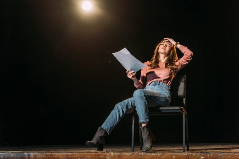 Actress on stage in a pink shirt and jeans feeling overwhelmed by an intense role.