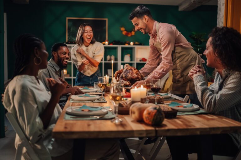 Laughing friends enjoying a festive thanksgiving dinner, complete with a delicious turkey feast.